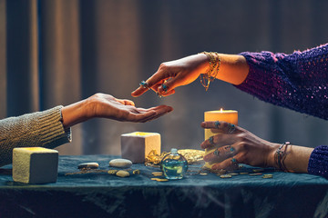 Magic gypsy woman reading palm lines around candles and other magical accessories. Witch during fortune telling palmistry, prediction the future life and divination ritual