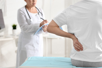 Female orthopedist examining patient with injured back in clinic, closeup