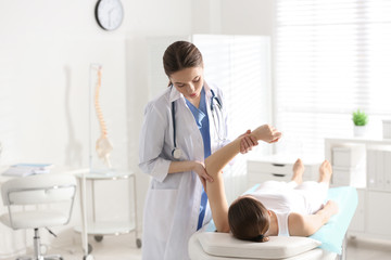 Obraz premium Female orthopedist examining patient's arm in clinic