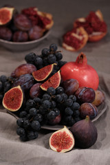 Fruit plate: figs, black grapes, plums, pomegranate. The concept of a healthy diet and a healthy lifestyle. Selective focus
