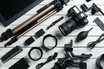 Flat lay composition with camera and video production equipment on white wooden table