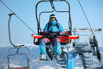 Fototapeta premium Man using chairlift at mountain ski resort. Winter vacation