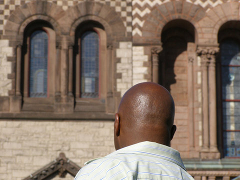 Back view of a well-shaven African American just in front of an old church in USA - Powered by Adobe