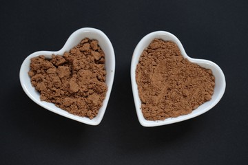 Guarana powder in plates hearts  on a  black background.Portion of Guarana Powder