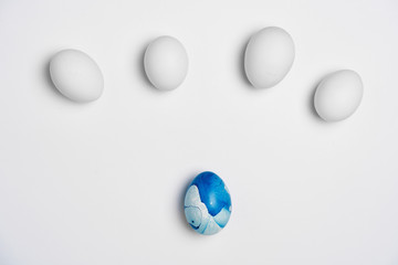 blue art and four white eggs on white background isolated