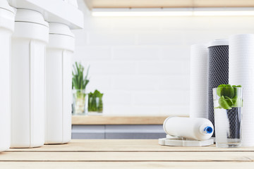 A glass of clean water with osmosis filter and cartridges in a kitchen interior. Concept Household...