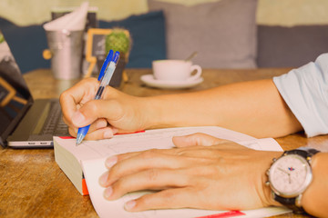 Obraz na płótnie Canvas Businessman writing note on oreading book with laptop on table.
