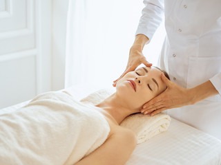 Beautiful woman enjoying facial massage with closed eyes. Spa treatment concept in medicine