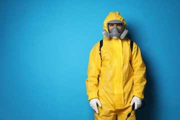 Man wearing protective suit with insecticide sprayer on blue background, space for text. Pest control - Powered by Adobe