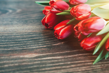 Red tulips on a dark wooden background