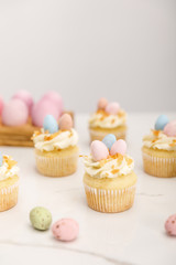 Selective focus of delicious easter cupcakes with painted quail eggs on grey background
