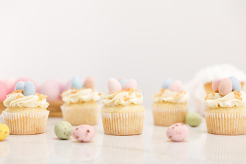 Selective focus of easter cupcakes with painted quail eggs on grey background