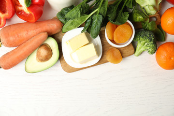 Different natural food rich in vitamin A on white wooden table, flat lay. Space for text