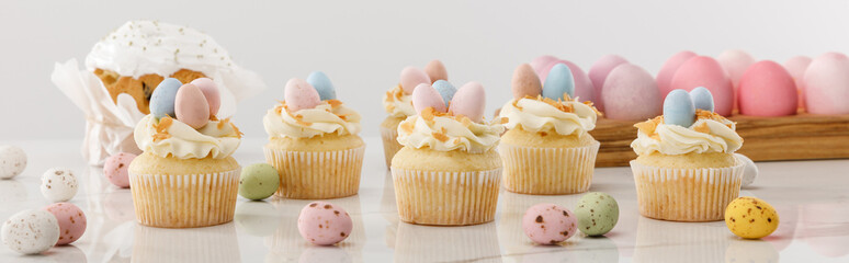 Delicious cupcakes with colorful painted chicken and quail eggs near easter cake on grey...