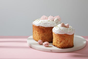 Delicious easter cakes and quail eggs on round board on grey and pink