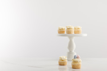 Tasty easter cupcakes on cake stand isolated on grey