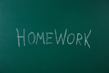 Word HOMEWORK written with chalk on green chalkboard