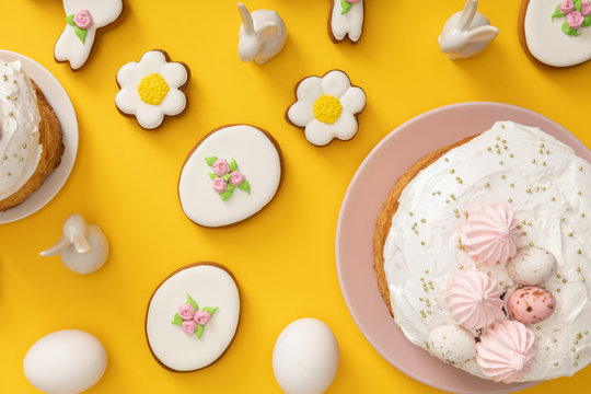Top view of easter cakes, chicken eggs, cookies and decorative bunnies on yellow background
