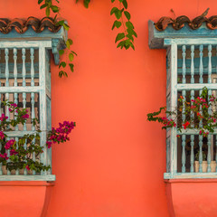 Spanish colonial style windows with wooden wrought and awning on vibrant color wall in Cartagena old town, Colombia.
