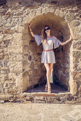 beautiful woman in a fashionable summer dress in the arch in an old stone fortress