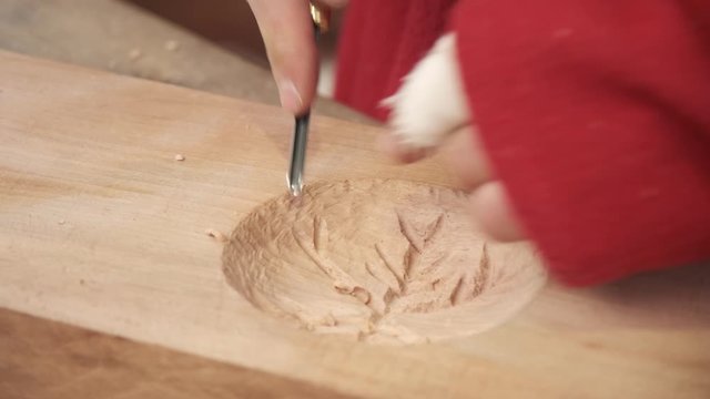 Wood carving close up hands. Young guy carves a chisel pattern on a tree. Fablab woodworking.