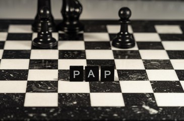 The acronym Pap for Password Authentication Protocol represented by black and white letter tiles on a marble chessboard with chess pieces