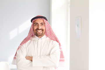 Positive arabic man smiling while standing in a white bright room