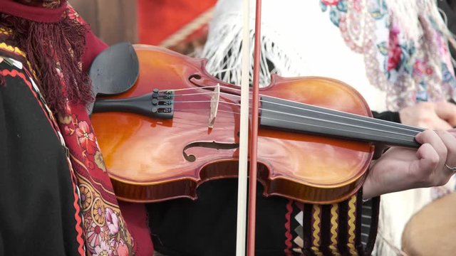 A girl plays the violin during a street performance. Close-up.