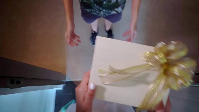 courier delivers the package and handing it to receiver, a girl in white robe taking the box of gifts on threshold of her hotel room