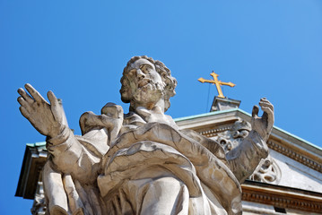 Low angle view of Saint Peter's statue against blue sky with cross in front of St. Paul church in Poland.
