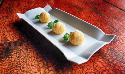 Chinese dessert nicely presented in white porcelain plate on old wooden lacquered red table.