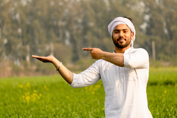 Indian farmer with empty hand for product putting and pointing finger at empty hand