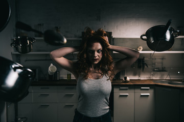 demonic woman with levitating kitchenware in kitchen