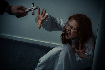 exorcist holding cross in front of screaming obsessed girl