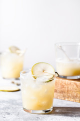A short glass of refreshing pear soda water mocktail or cocktail on gray concrete background. Non alcoholic summer drink. Selective focus, vertical orientation, copy space