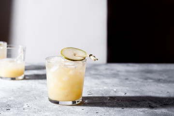 A short glass of refreshing pear soda water mocktail or cocktail on gray concrete background. Non alcoholic summer drink. Horizontal orientation, copy space