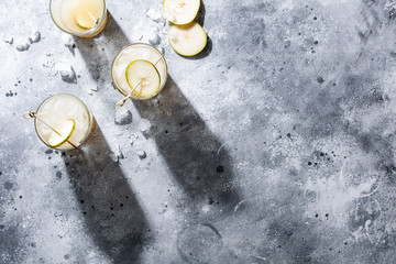A short glass of refreshing pear soda water mocktail or cocktail on gray concrete background. Non alcoholic summer drink. Horizontal orientation, copy space, top view, flat lay