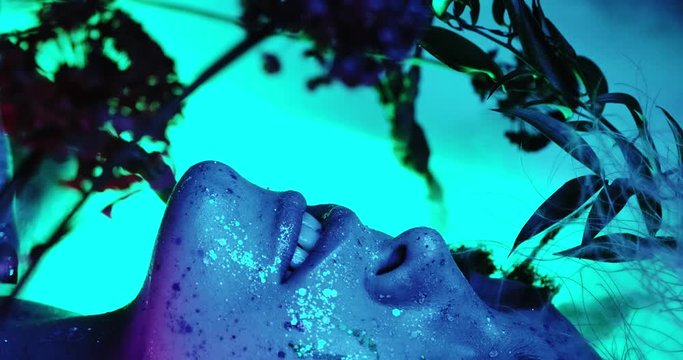 Lips kiss in neon UV lights. Beauty sexy model lips close-up, disco. Woman mouth closeup. Metallic lipstick. Purple and blue ultraviolet lights. Slow motion 4K UHD video