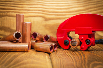 Red pipe cutter and copper pipes with connectors for plumbing repairs on vintage boards