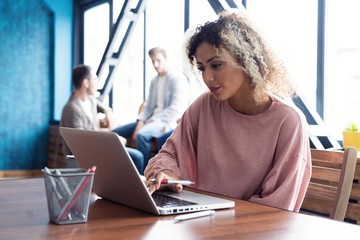Beautiful business African lady is looking at camera and smiling while working in office