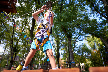 Little boy overcomes the obstacle in the rope park.