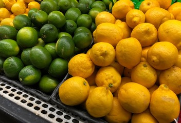 Piles of green lime and lemon fruits at the fresh produce section of a market