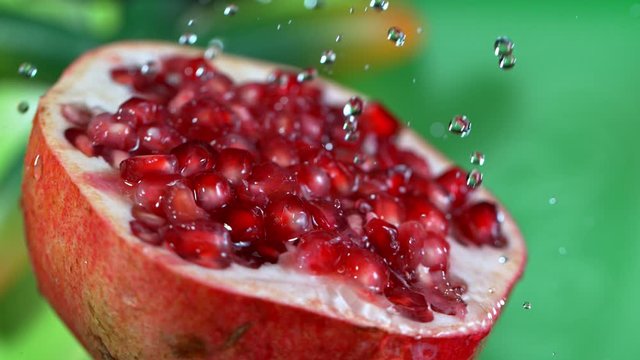 Super Slow Motion Shot of Pouring Water on Fresh Pomegranate at 1000fps.
