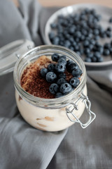 Delicious dessert: tiramisu in a glass jar and natural yogurt in a glass cup with fresh berries, strawberries and blueberries. 
