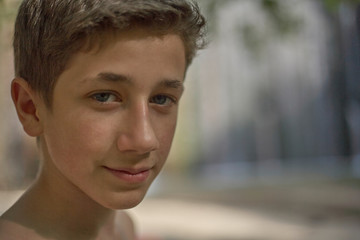 Fototapeta na wymiar Closeup of a handsome self-confident young teenager in summer relaxed happy mood on his face