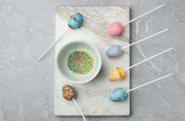 Egg shaped cake pops for Easter celebration on grey marble table, flat lay