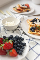 Beautiful breakfast: Viennese Belgian waffles decorated with berries, a plate with strawberries and blueberries