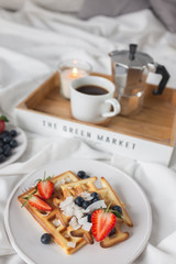 Beautiful breakfast in bed: Viennese Belgian waffles decorated with berries, a plate with strawberries and blueberries