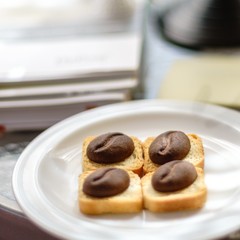 Brown cookies in the shape of cocoa beans in a white plate on a table with books