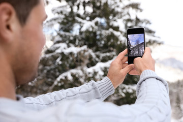 Man taking picture of snowy tree outdoors, closeup